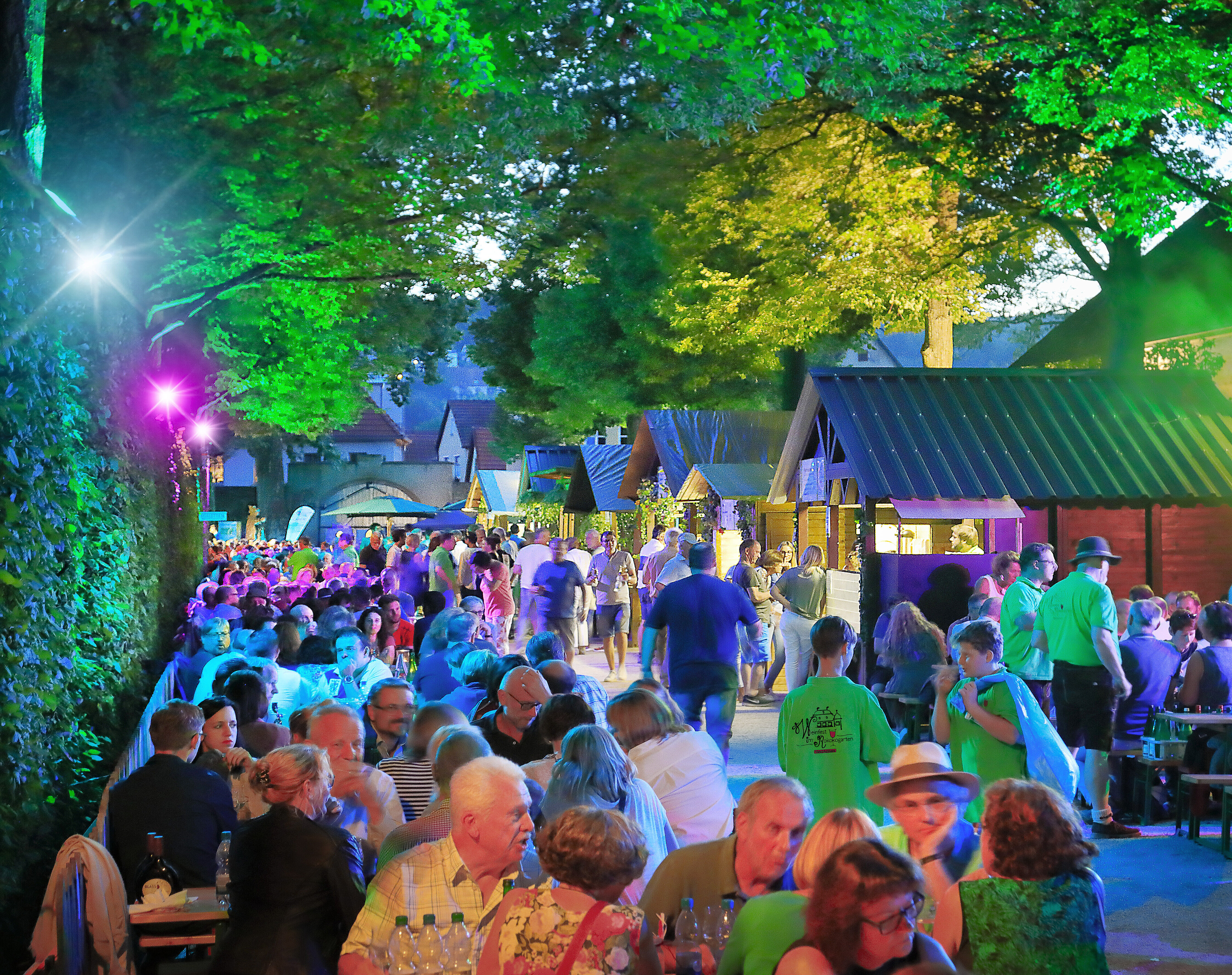 Weinfest im Rokokogarten Veitshöchheim. Besucher auf Bierbänken beim Schöppeln, rechts Verkaufsstände