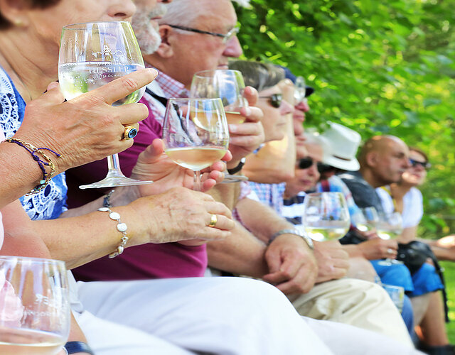 Besucher sitzen im Rokokogarten Veitshöchheim und trinken Wein