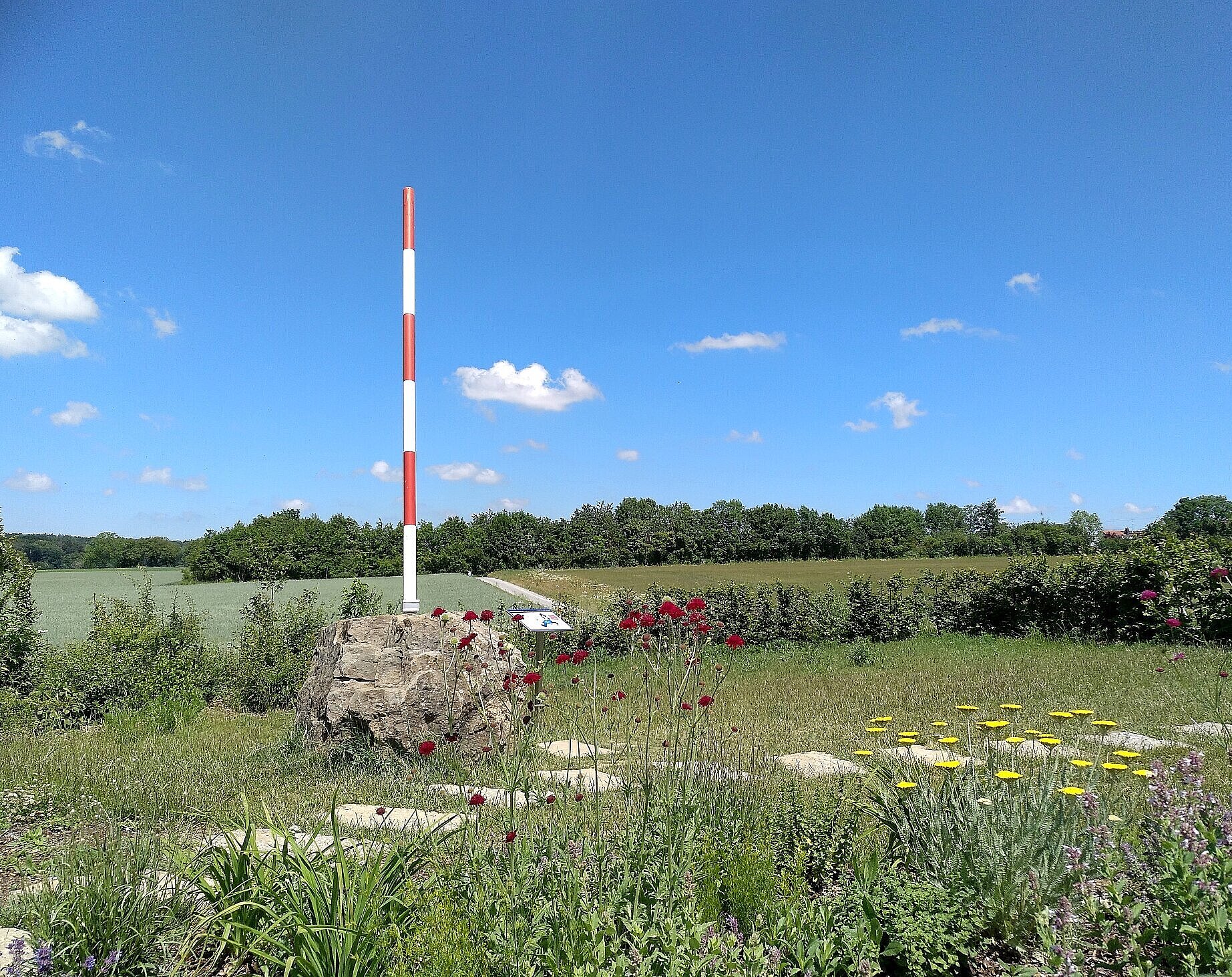 Mittelpunkt der EU in Gadheim. Findling mit Mast, der Mittelpunkt markiert.