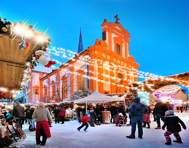 Altort-Weihnachtsmarkt in Veitshöchheim. Buden, Besucher, im Hintergrund die Kirche.